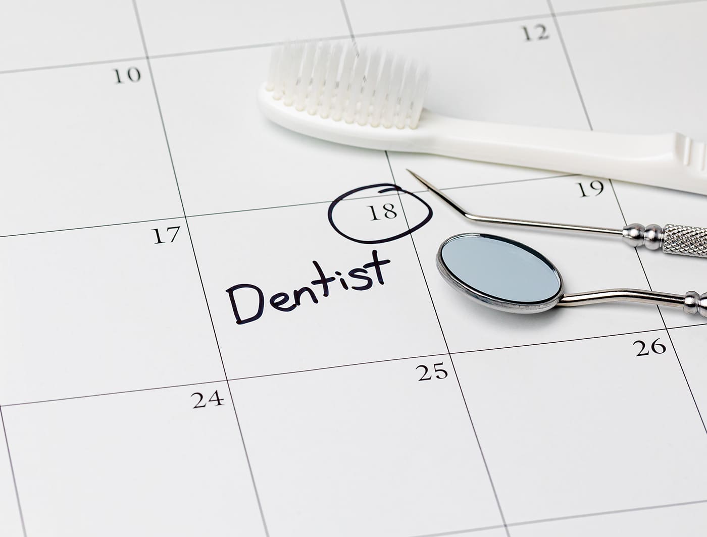 Dentist appointment reminder on calendar with toothbrush and den