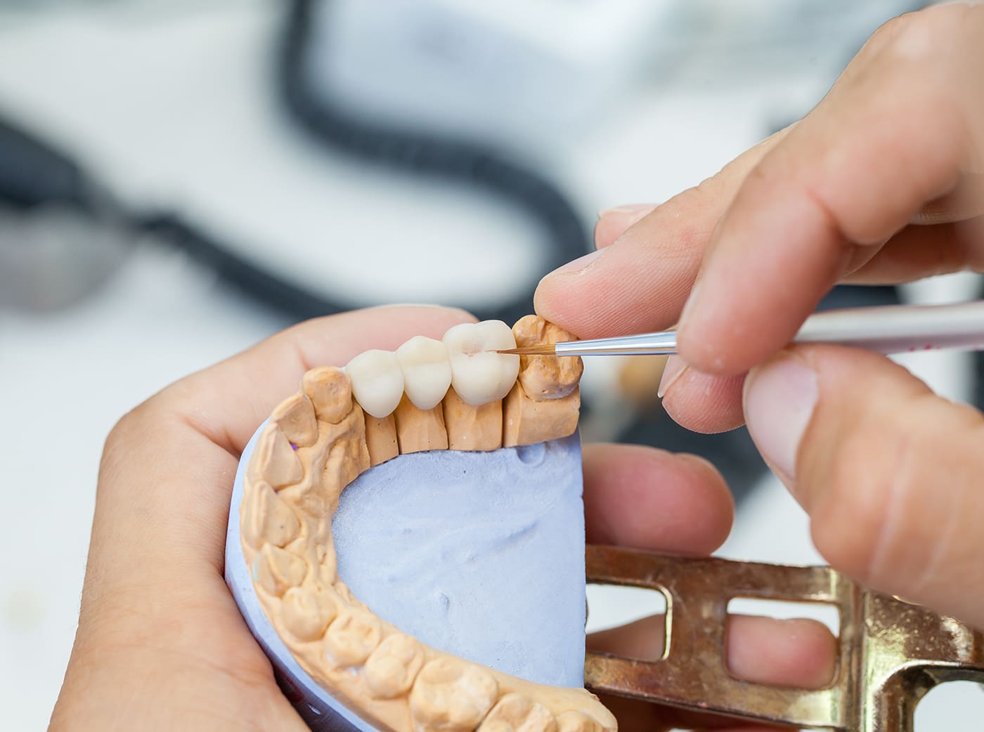 dental technician works by brush with dental bridge