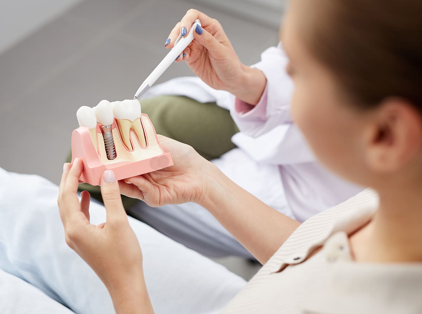 young woman holding tooth model during consultation in dentists office